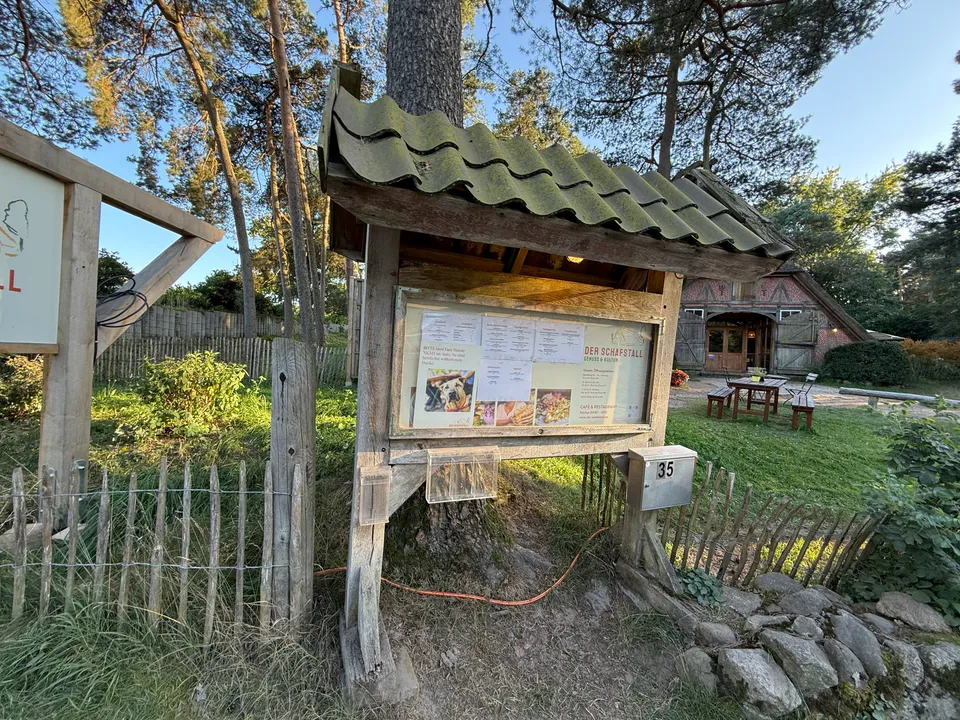 Aushangkasten mit Speisekarten des Schafstalls und Briefkasten Nummer 35 vor Fachwerkhaus mit Gartentischen