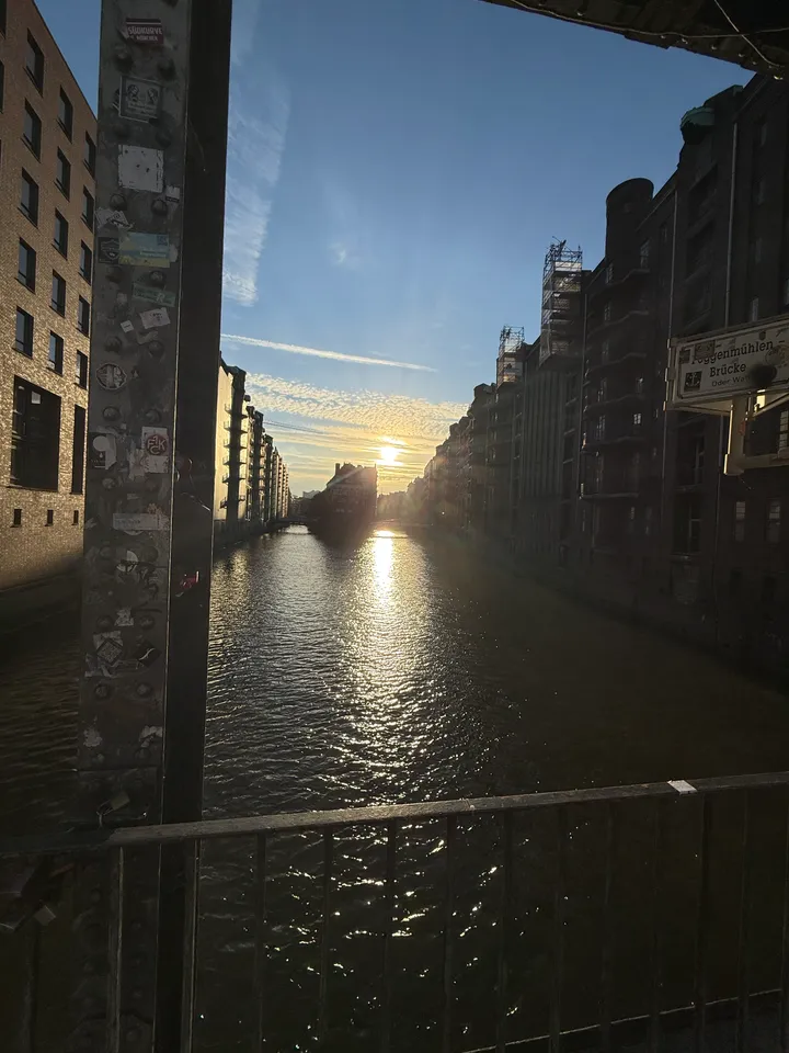 Fleet im Gegenlicht der tiefstehenden Sonne, von der Brücke aus gesehen, mit Brückenträger und Straßenschild im Vordergrund