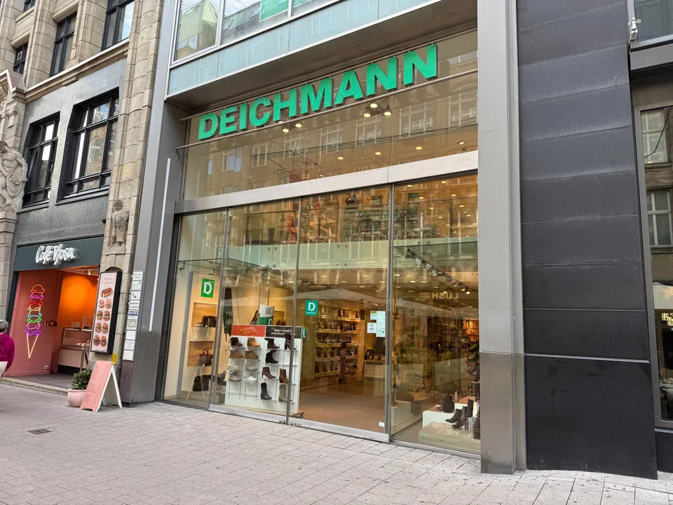 Ladenfront einer DEICHMANN-Filiale mit grünem Schriftzug und Glasfassade, links daneben ein Eiscafé in der Fußgängerzone