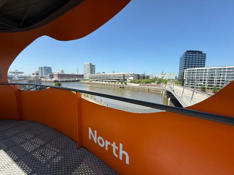 Blick nach Norden über Hafenbecken und Brücke auf Bürogebäude, Hochhaus und entfernte Kirchtürme