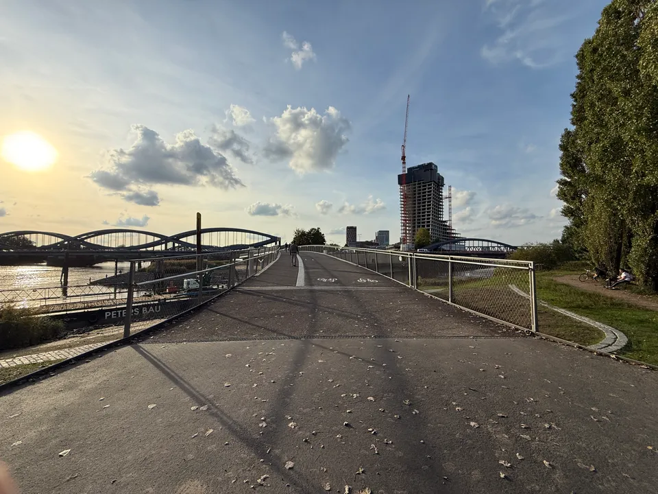 Rampe eines Fuß- und Radwegs mit Fahrradmarkierung, links Elbbrücken, im Hintergrund Hochhausrohbau mit Kran