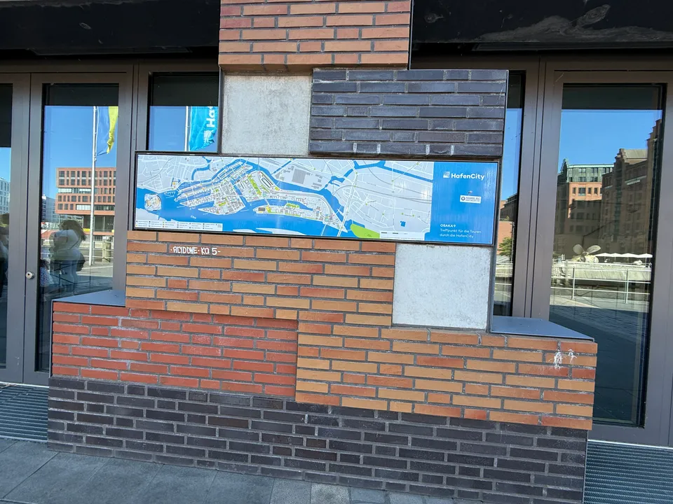 Übersichtskarte der HafenCity mit Hinweis auf den Tourentreffpunkt OSAKA 9 in einem Klinkerpfeiler