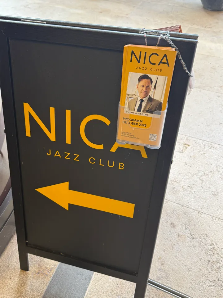 Schwarzer Kundenstopper mit gelbem Schriftzug „Nica Jazz Club“, Pfeil nach links und angehängten Programmflyern