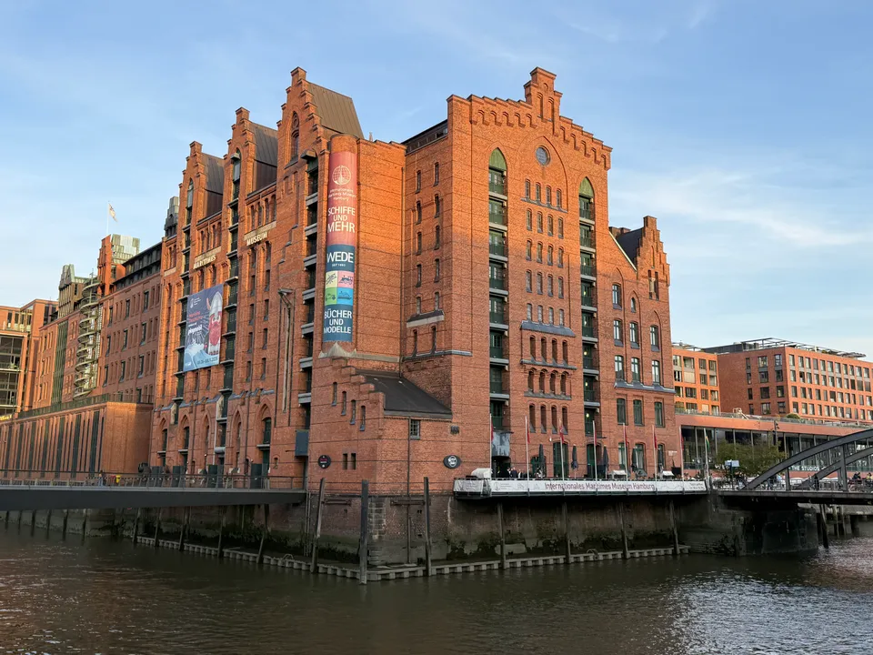 Backsteinspeicher des Internationalen Maritimen Museums an einem Fleet in der Abendsonne, links und rechts Brücken