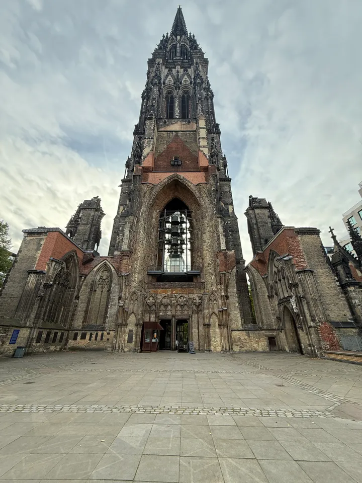 Frontansicht des Turms der Kirchenruine St. Nikolai mit Glockenspiel, gläsernem Aufzug und Seitenschiffresten
