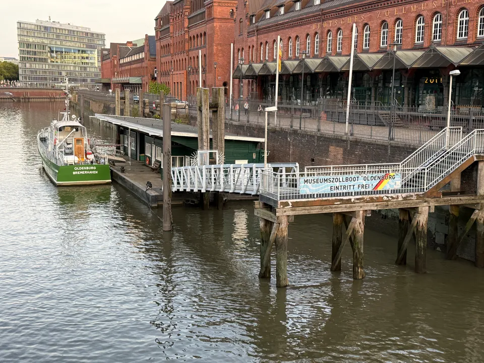 Grünes Museumszollboot Oldenburg an einem Ponton im Fleet vor dem Backsteingebäude des Deutschen Zollmuseums