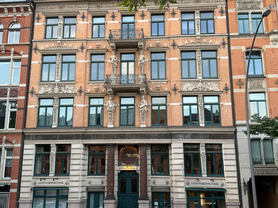 Historistische Backsteinfassade mit Stuckfiguren, schmiedeeisernen Balkonen und Säulenportal, über dem die Hausnummer Zippelhaus 3 steht