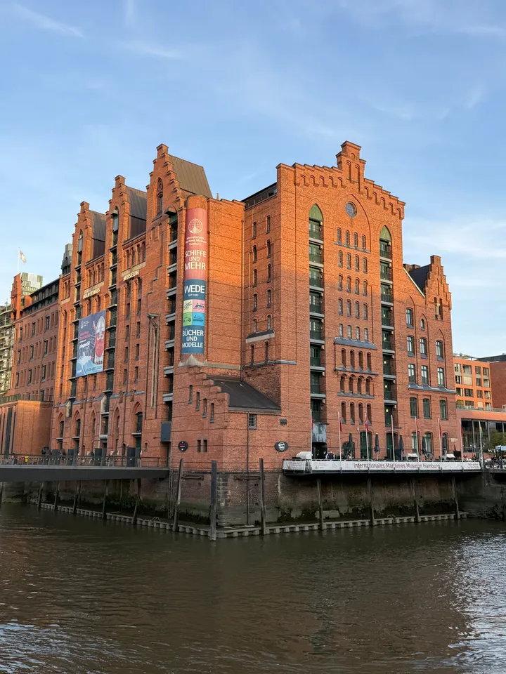 Rote Backsteinfassade des Internationalen Maritimen Museums mit Staffelgiebeln über dem Wasser im warmen Abendlicht
