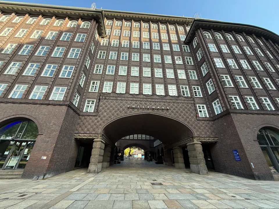 Symmetrische Klinkerfassade des Chilehauses mit mittiger Bogendurchfahrt und Schriftzug Chilehaus über gepflastertem Vorplatz