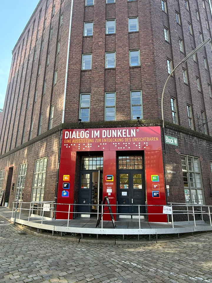 Hoher Backstein-Speicherbau mit rotem Eingangsportal der Ausstellung Dialog im Dunkeln und Rampe davor