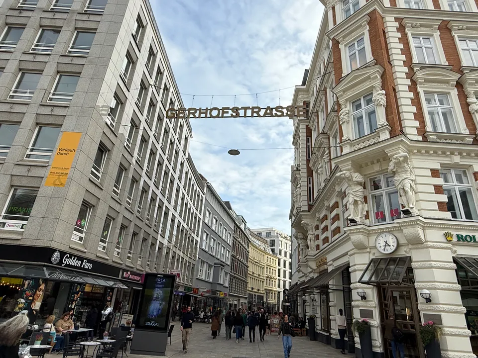 Fußgängerzone Gerhofstraße mit hängendem Straßenschriftzug, Café links und verziertem Gründerzeit-Eckhaus mit Atlanten rechts