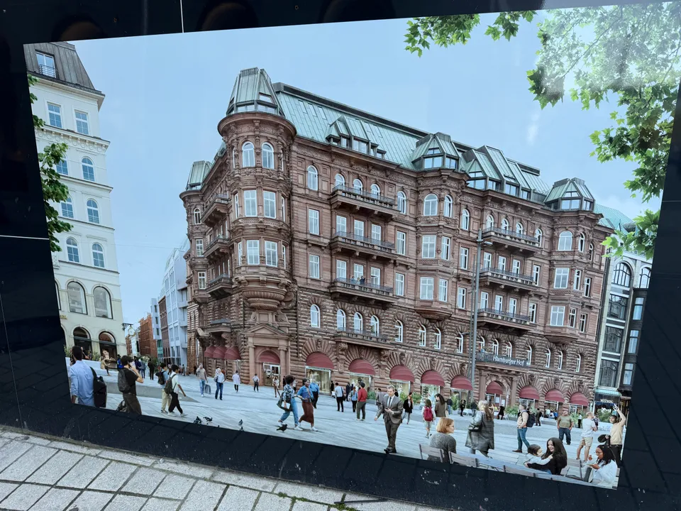Visualisierung auf einem Bauzaun: roter Sandsteinbau mit Ecktürmen, grünem Kupferdach und belebtem Platz davor