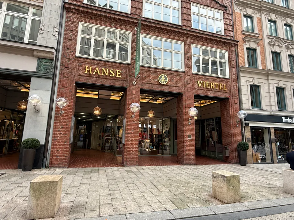 Backsteinfassade mit goldenem Schriftzug Hanse Viertel über drei überdachten Passageneingängen in einer Fußgängerzone