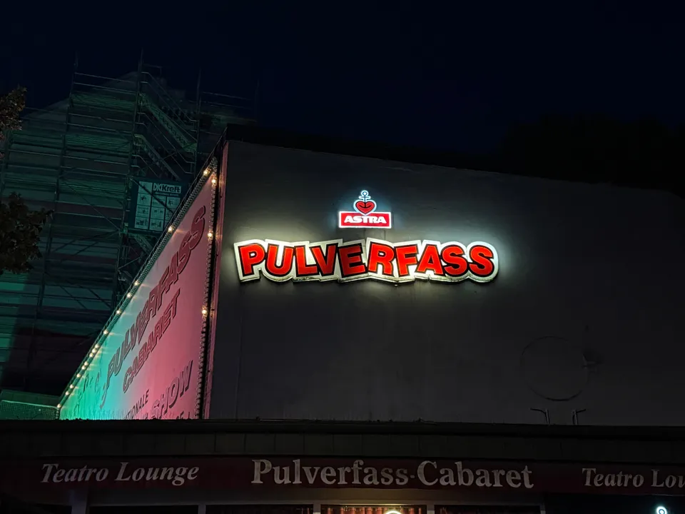 Rote Leuchtschrift Pulverfass mit Astra-Logo auf heller Fassade, darunter Blende Pulverfass-Cabaret, nachts