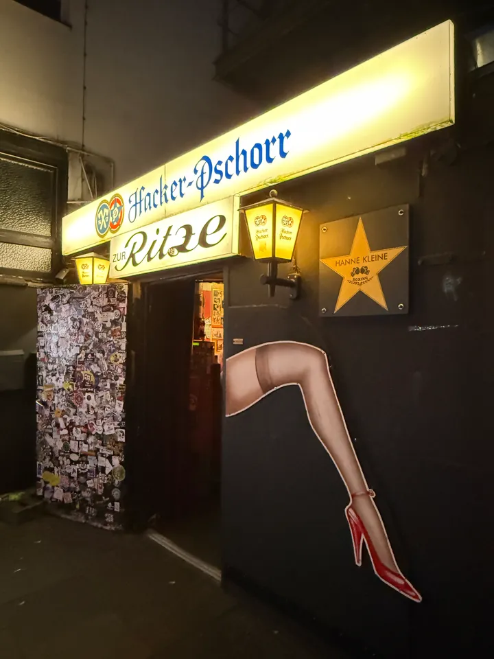Seitliche Ansicht des Eingangs der Kneipe Zur Ritze mit aufgemaltem Frauenbein und Stern „Hanne Kleine“