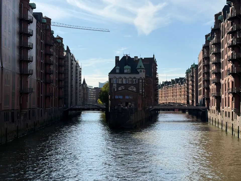 Wasserschloss auf einer Landspitze zwischen zwei Fleeten, gesäumt von roten Backsteinspeichern und zwei Stahlbogenbrücken