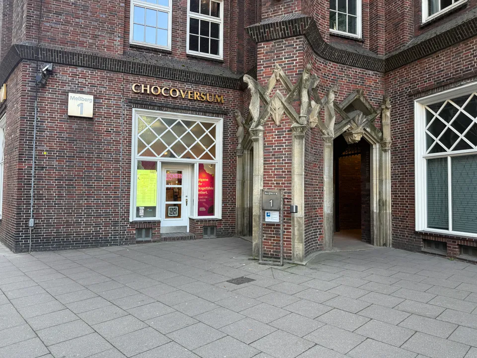 Eingang des Chocoversum mit goldenem Schriftzug, Rautenfenster und steinernem Spitzbogenportal an einer Backsteinfassade