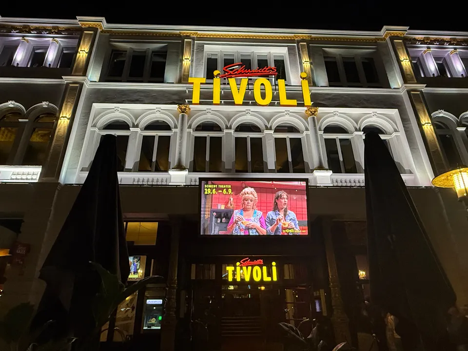 Beleuchtete historische Fassade des Schmidts Tivoli bei Nacht mit gelbem Leuchtschriftzug und Werbebildschirm über dem Eingang