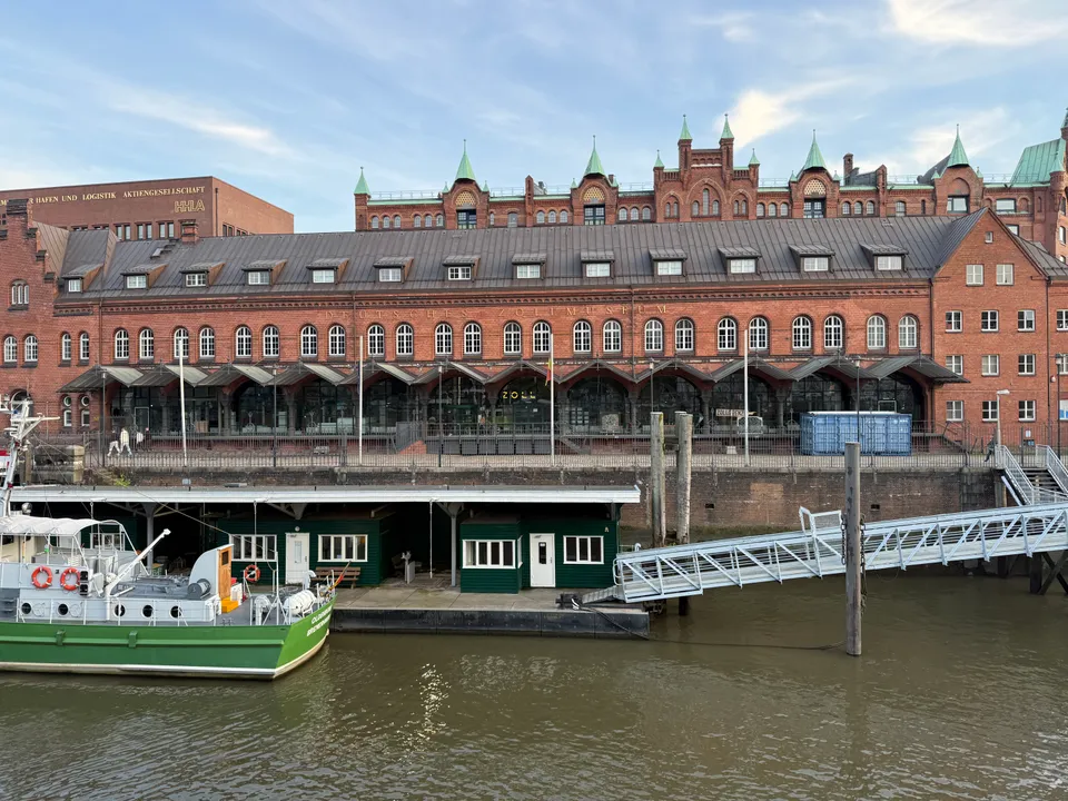 Backsteinfassade des Deutschen Zollmuseums am Zollkanal, davor ein grün-weißes Zollboot am Ponton mit Gangway