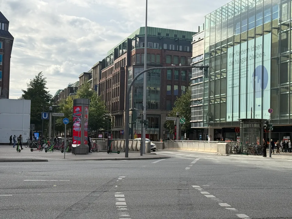 Kreuzung am Steintorwall mit Backstein-Eckhaus, Glasfassade, U- und S-Bahn-Schildern sowie abgestellten Fahrrädern und E-Rollern