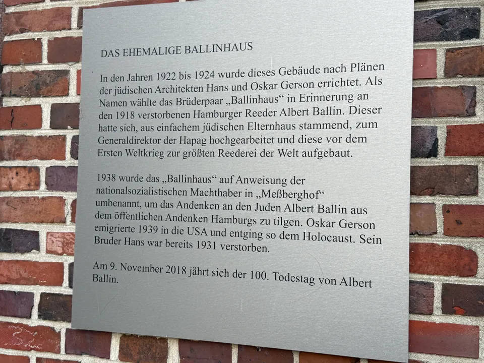 Metalltafel an Klinkerwand mit dem Titel „Das ehemalige Ballinhaus“ und Text zur Gebäudegeschichte