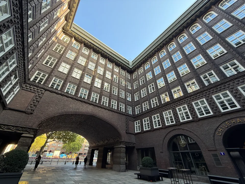 Innenhof des Chilehauses mit hohen Klinkerfassaden, Sprossenfenstern und Bogendurchfahrt unter klarem blauem Himmel