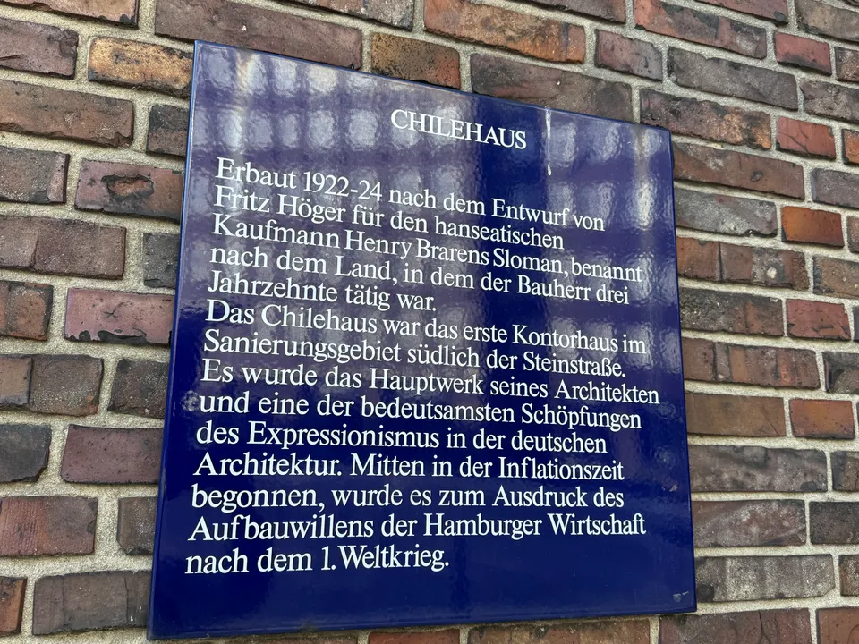 Blaue Emaille-Infotafel zum Chilehaus mit weißer Schrift an einer Klinkerwand, Baujahre 1922 bis 1924