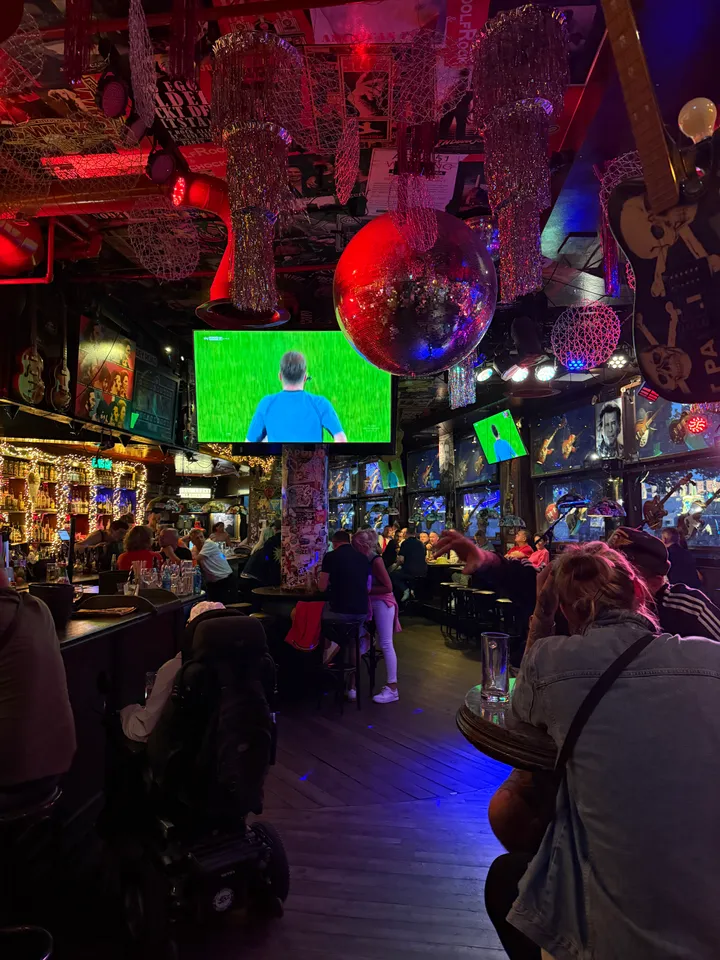 Gut besuchte Rockkneipe mit Discokugel, Fußballübertragung, beleuchteter Theke und Gästen an Stehtischen