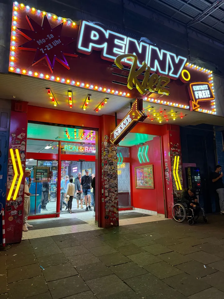 Nächtlicher Eingang des Penny-Markts auf der Reeperbahn mit roter, bunt beleuchteter Fassade und Neonschrift „Penny Kiez“