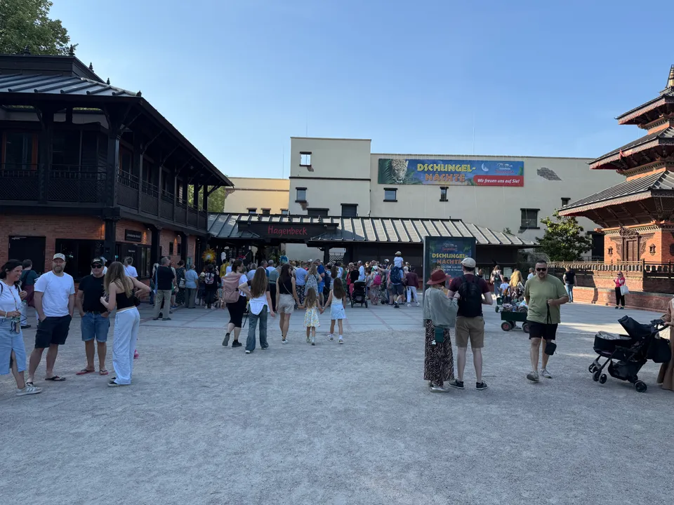 Besucher auf dem Vorplatz vor dem Eingangstor des Tierparks Hagenbeck, links ein Backsteinbau, rechts eine Pagode