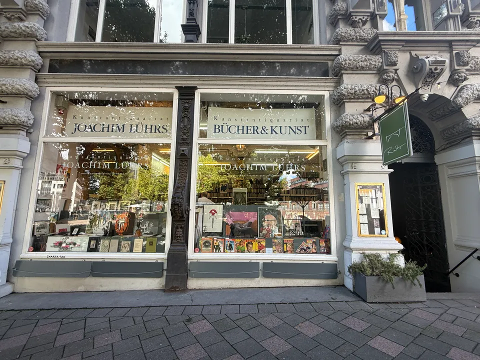 Schaufenster des Kunstantiquariats Joachim Lührs mit Grafiken und Zeitschriften in verzierter historischer Steinfassade, rechts Rundbogeneingang