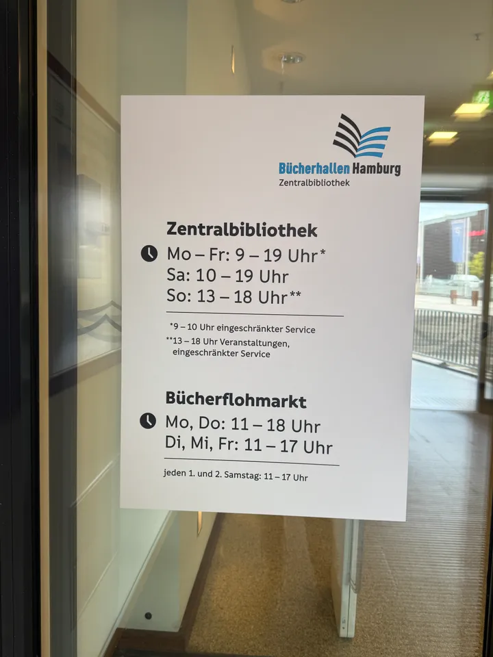 Aushang an Glastür mit Öffnungszeiten der Zentralbibliothek und des Bücherflohmarkts der Bücherhallen Hamburg