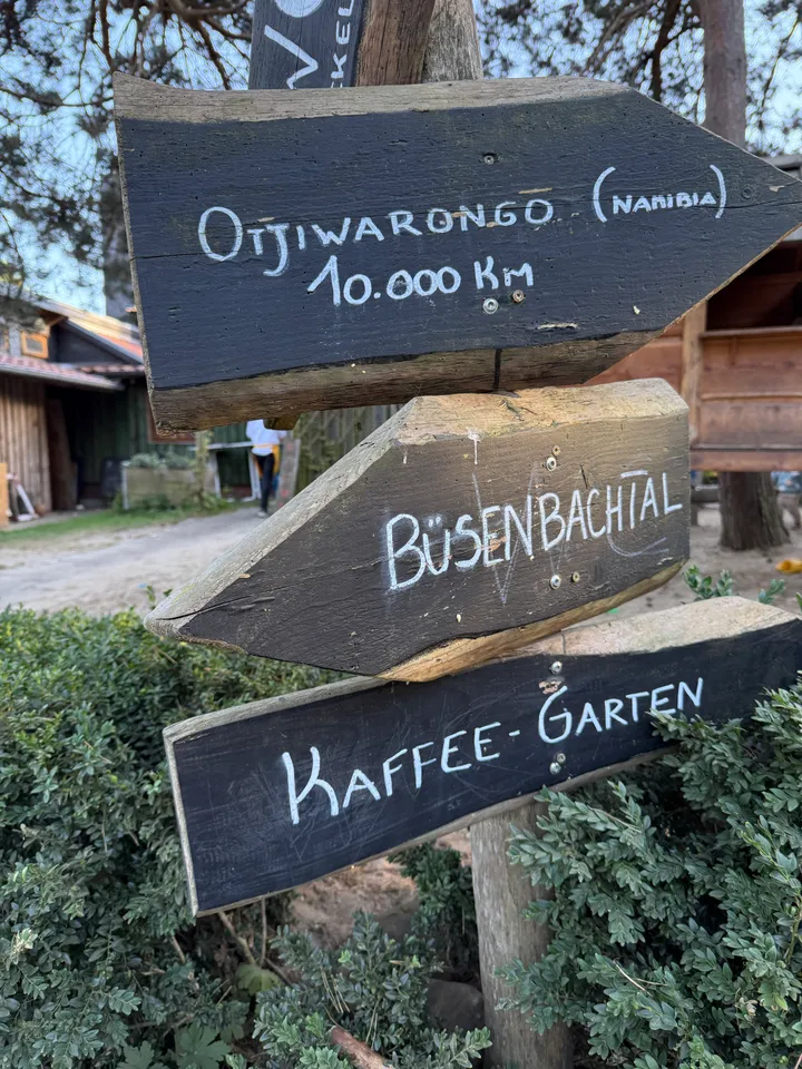 Hölzerner Wegweiser mit Schildern nach Otjiwarongo, zum Büsenbachtal und zum Kaffee-Garten