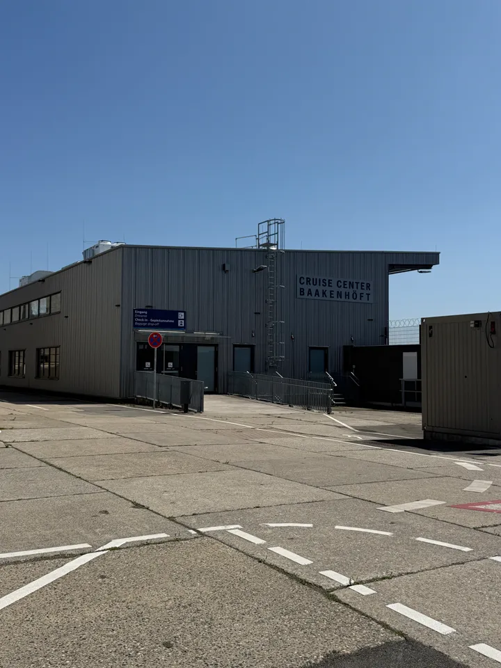 Graue Halle des Cruise Center Baakenhöft mit Eingang, Wegweiser und markierter Betonfläche davor