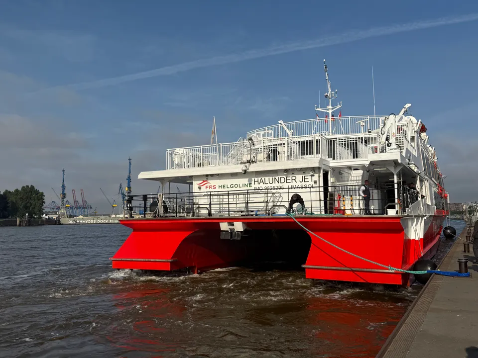 Heck des Katamarans „Halunder Jet“ an der Elbe, im Hintergrund Hafenkräne und das Dock von Blohm+Voss