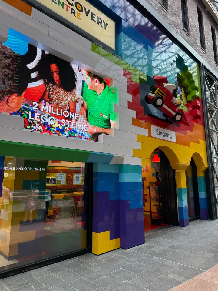 Bunte LEGO-Fassade mit Schriftzug Discovery Centre, Videowand „2 Millionen LEGO Steine“ und Eingangsbögen