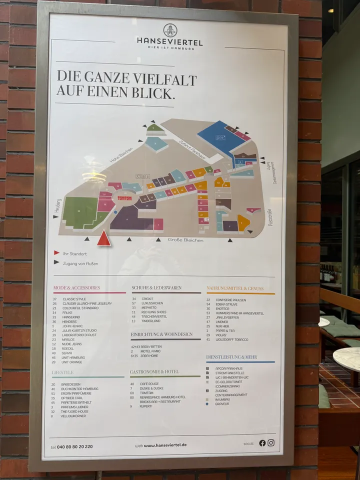 Lageplan und Geschäftsverzeichnis der Einkaufspassage Hanseviertel auf einer Tafel an einer Backsteinwand